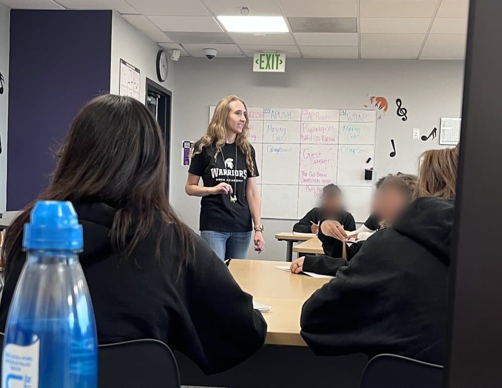 Taylor teaching a high school class, standing in front of the whiteboard